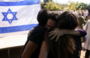 <p>People hug in front of Israeli flag, as friends and family mourn Vivian Silver, 74, a Canadian-born peace activist from Kibbutz Beeri who was killed in the deadly October 7 attack by Palestinian Islamist group Hamas from the Gaza Strip, at a memorial service, at Kibbutz Gezer, Israel November 16, 2023. REUTERS/Ronen Zvulun</p>