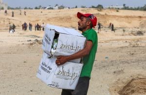 <p>A Palestinian man carries food items collected from aid packages dropped from an airplane, amid a hunger crisis, in Deir Al-Balah, in the central Gaza Strip, August 12, 2025. REUTERS/Ramadan Abed</p>