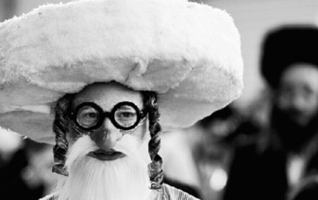 <p>An Israeli ultra-orthodox Jewish man wears a mask as part of a costume as he walks in the street during celebration of the holiday of Purim, in the Mea Shearim neighborhood of Jerusalem, Sunday, March 27, 2005. The Purim holiday, wear many Jews dress in costumes, celebrates Esther's miraculous achievement when she saved the Jewish people from extinction during the Babylonian captivity. (AP Photo/Kevin Frayer)</p>